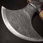 Close-up of a hand-forged carbon steel axe blade with a polished cutting edge and hammered dark texture.