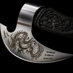 steel axe blade etched with a dragon design, next to a dark carved wooden handle with knot work engraving, on a black background.